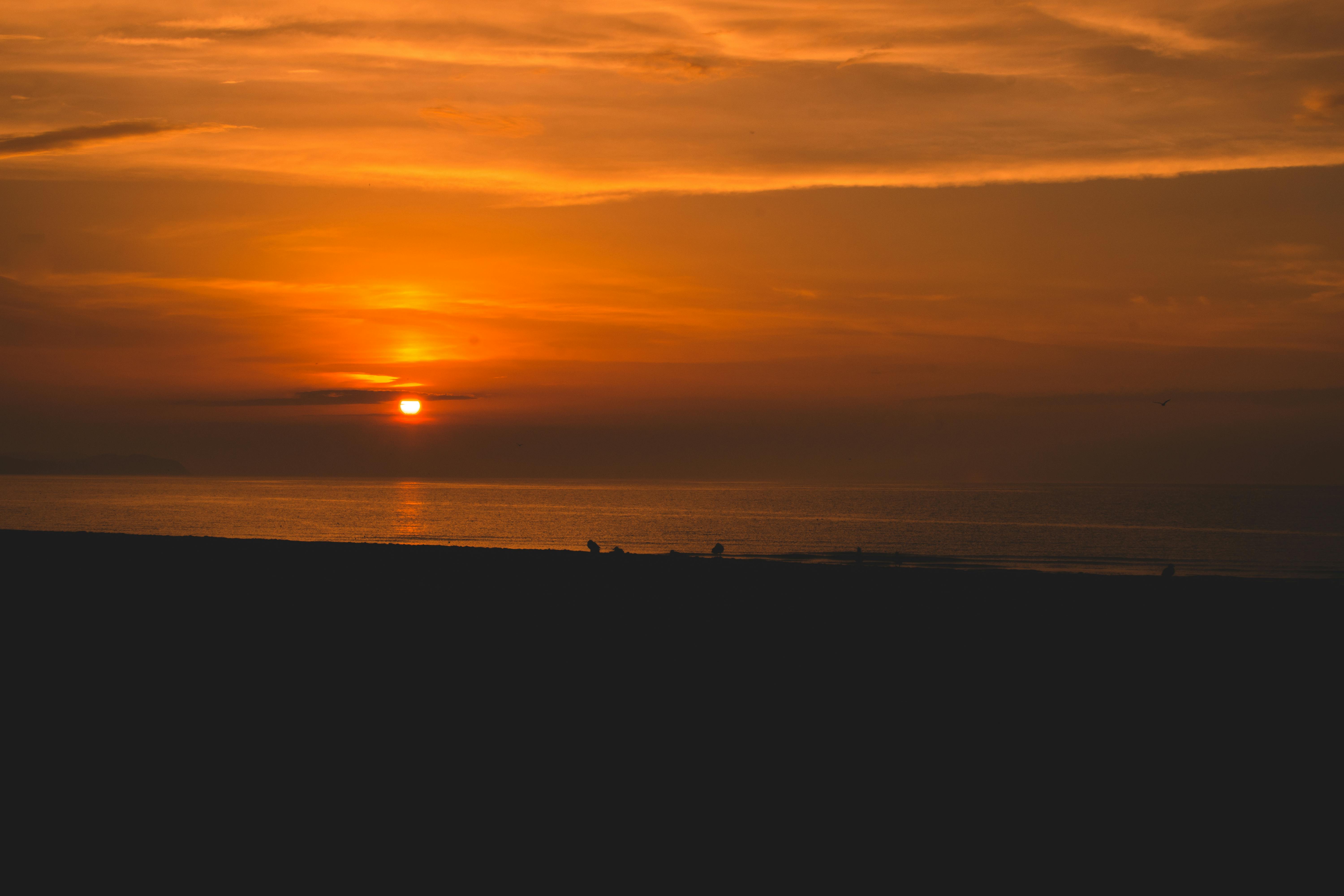 A breathtaking sunset over a tranquil sea, featuring vivid orange and yellow hues.