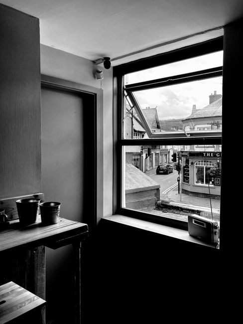 Interior of simple room with tiny metallic buckets on wooden shelf and old retro radio receiver on windowsill