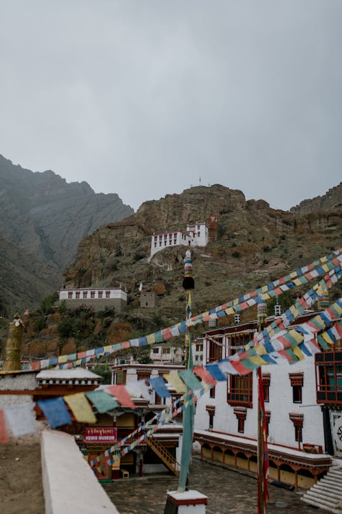 Colorful many flags hanging on street near ancient Hemis monastery with pillars located in mountainous terrain in India against gray sky