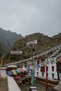 Colorful many flags hanging on street near ancient Hemis monastery with pillars located in mountainous terrain in India against gray sky