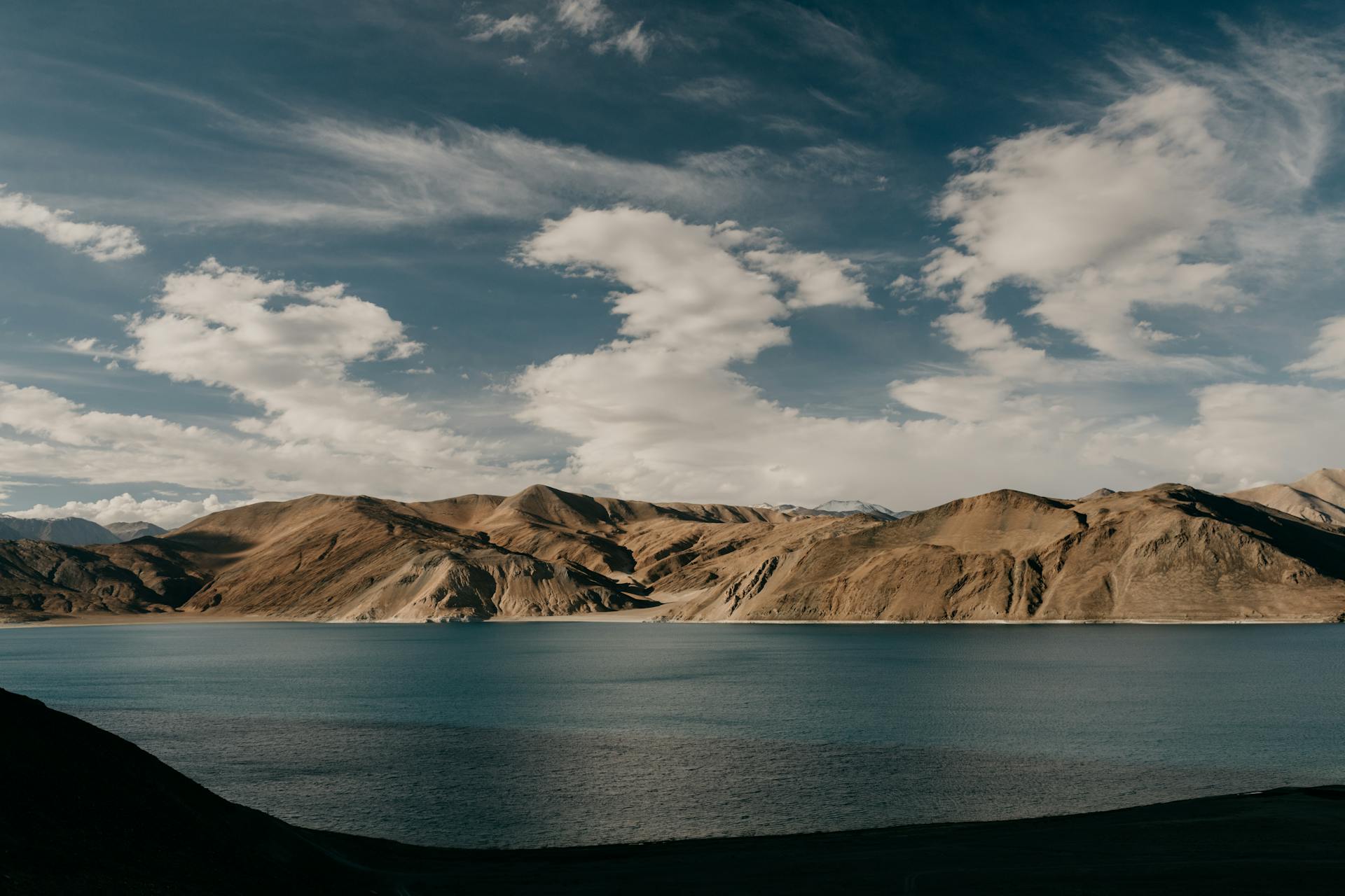 Azure sea cloudy sky flowing near range of rocky cliffs against cloudy sky in nature on summer day at seaside