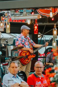 Colorful live music performance featuring an electric guitarist on stage in a vibrant setting.