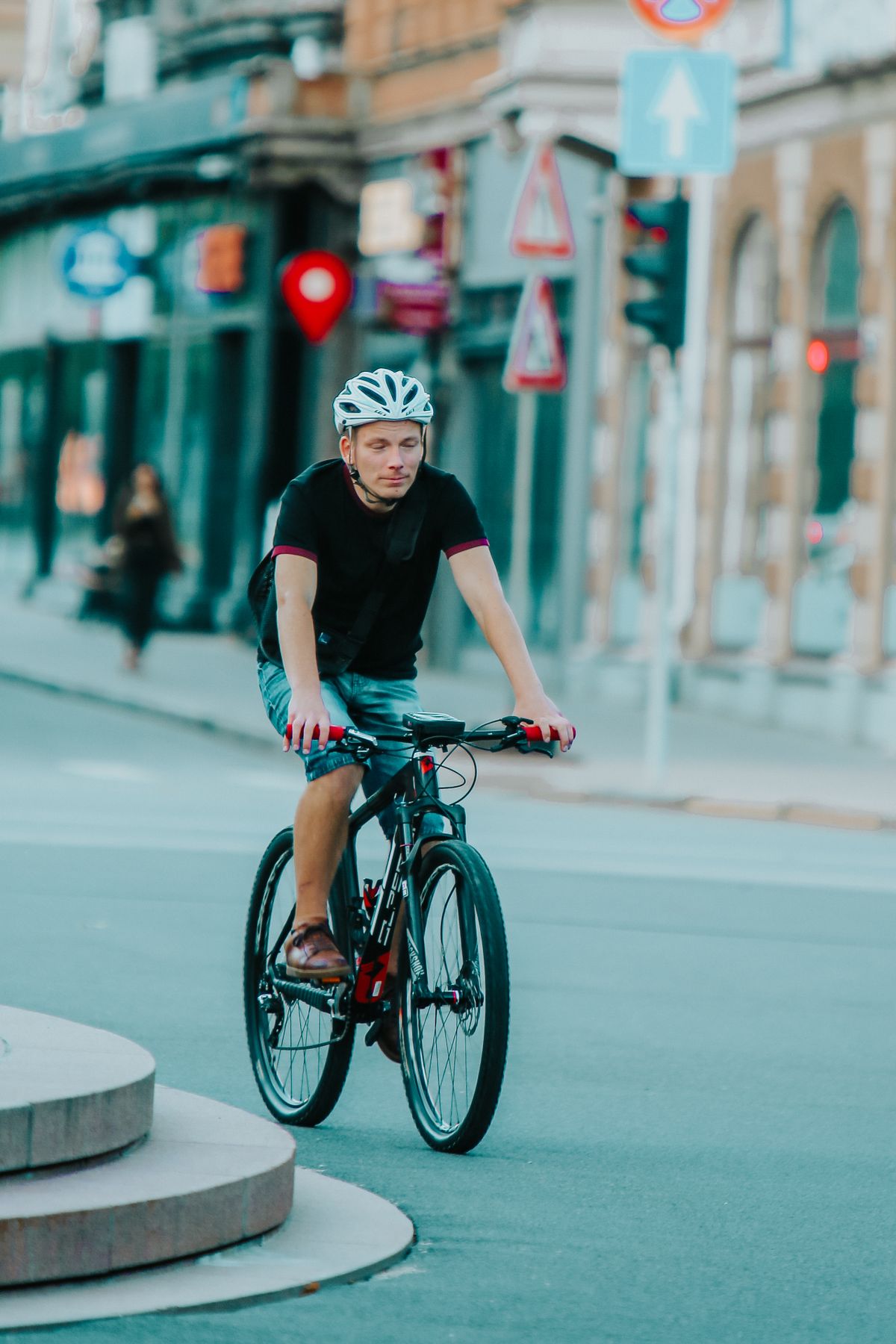 Helmeted cyclist riding a bicycle through an urban environment
