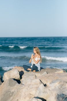 一名女子在平静的大海边的岩石海滩上冥想