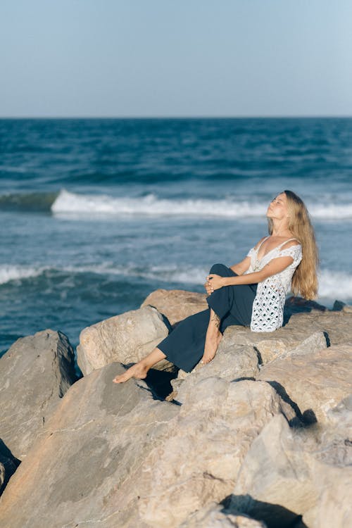Woman in Black and White Polka Dot Dress Sitting on Brown Rock Near ...