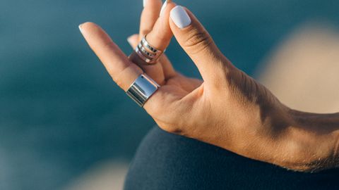 Serene close-up of a hand meditating outdoors with a blurred background.