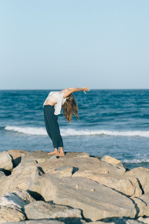 Woman Doing Yoga on Rocky Shore