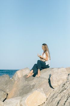 蔚蓝的天空下，一名年轻女子平静地坐在海边的岩石上冥想