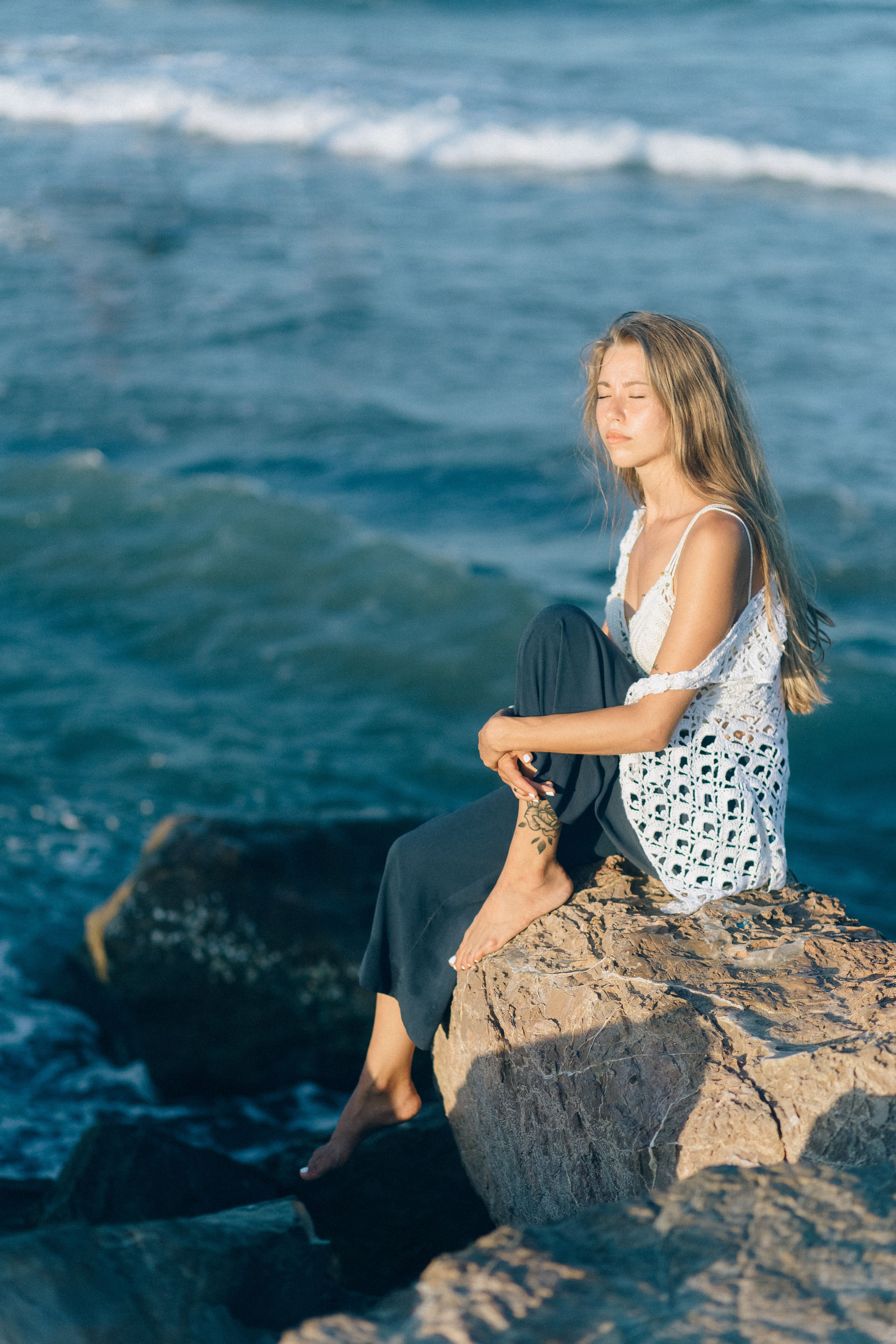 Woman Sitting on the Rocks Near Sea · Free Stock Photo