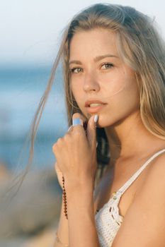 日落时分，海滩上一位留着金色长发的年轻女子的肖像