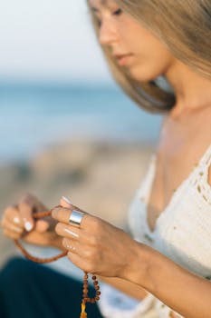 Close-up of a woman meditating outdoors with mala beads, capturing a serene and peaceful moment.