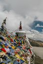 Wall of colorful flags hanging near stone tower of ancient monastery located in mountainous area against cloudy sky in nature in town