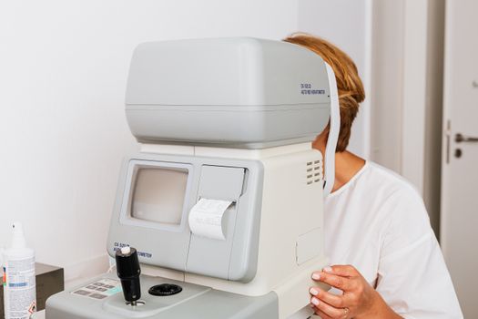 特写图：验光师在临床环境中使用自动验光仪进行眼部检查
