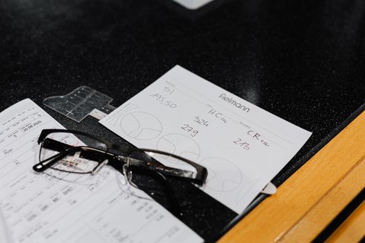 Eyeglasses resting on various forms on a black surface, symbolizing vision and assessment.