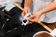 室内黑暗表面上用镜片布清洁太阳镜的详细视图
