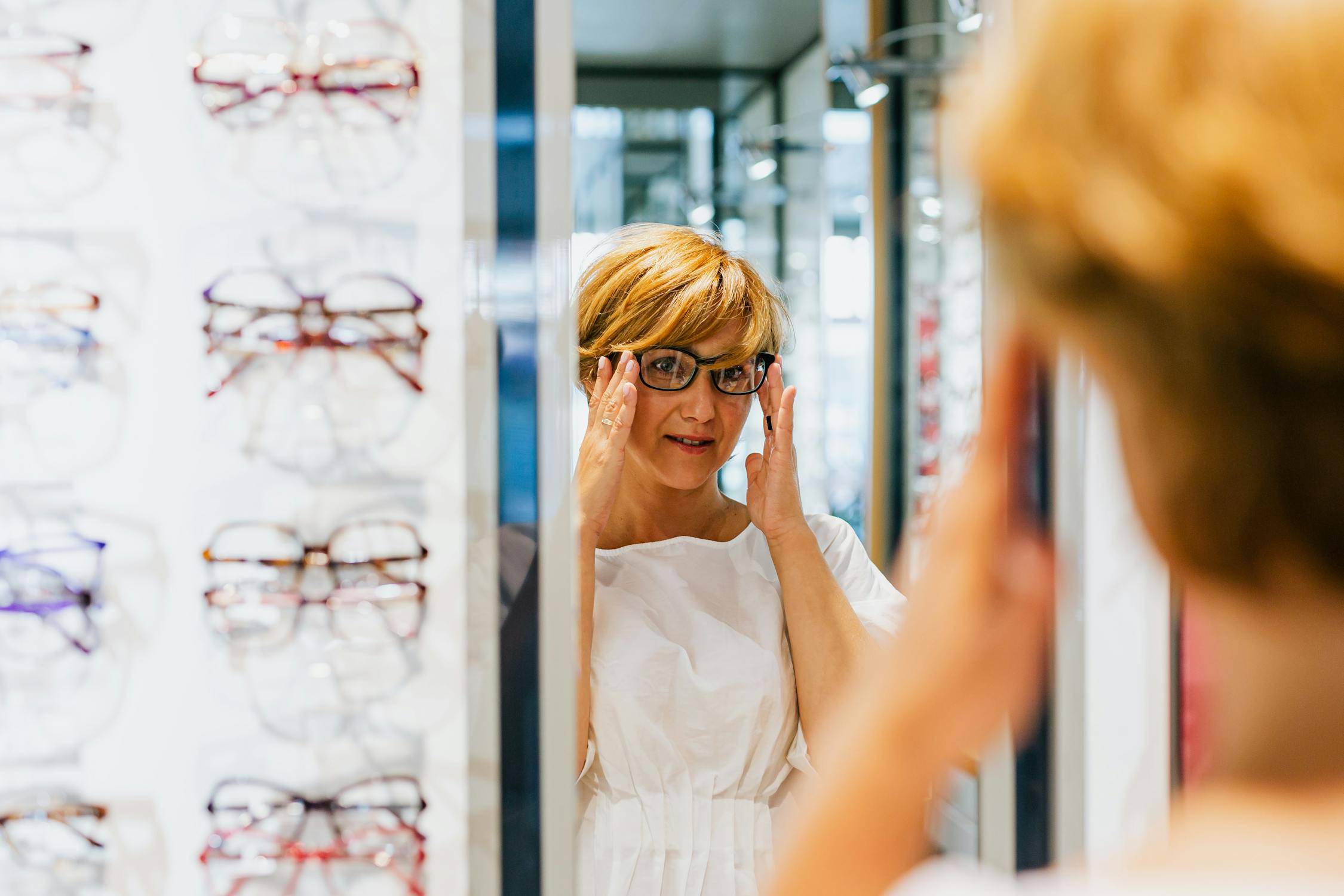Woman trying on glasses in an optics shop.