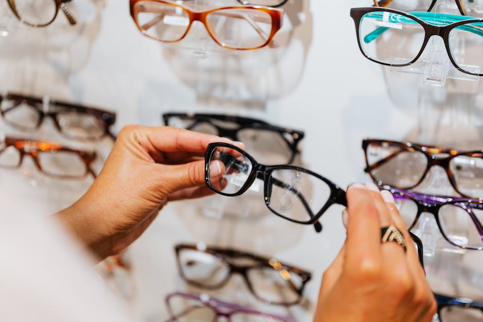 Detailed view of a person choosing eyeglasses from a wall display in a store.