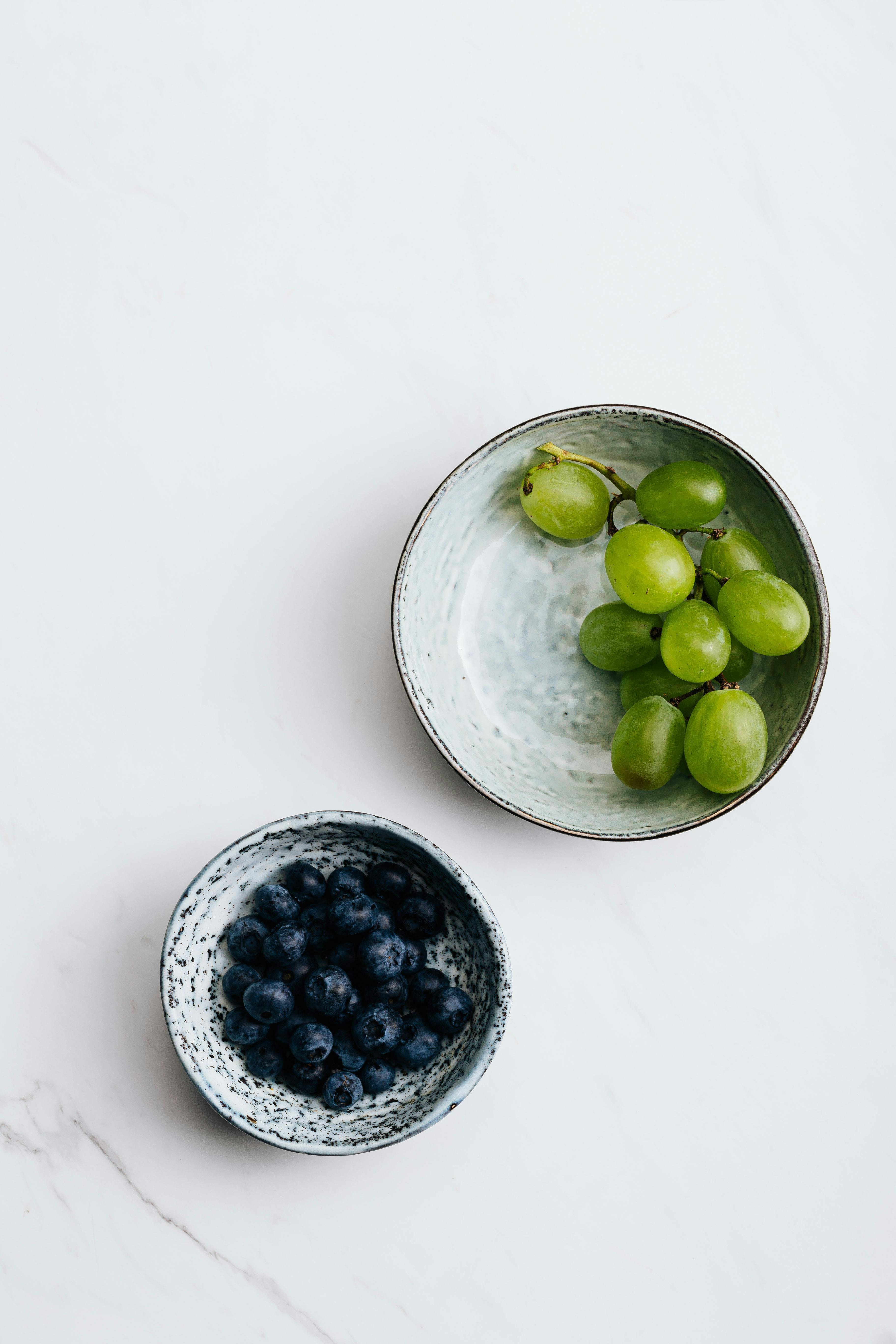 green grapes and blueberries in white ceramic bowl