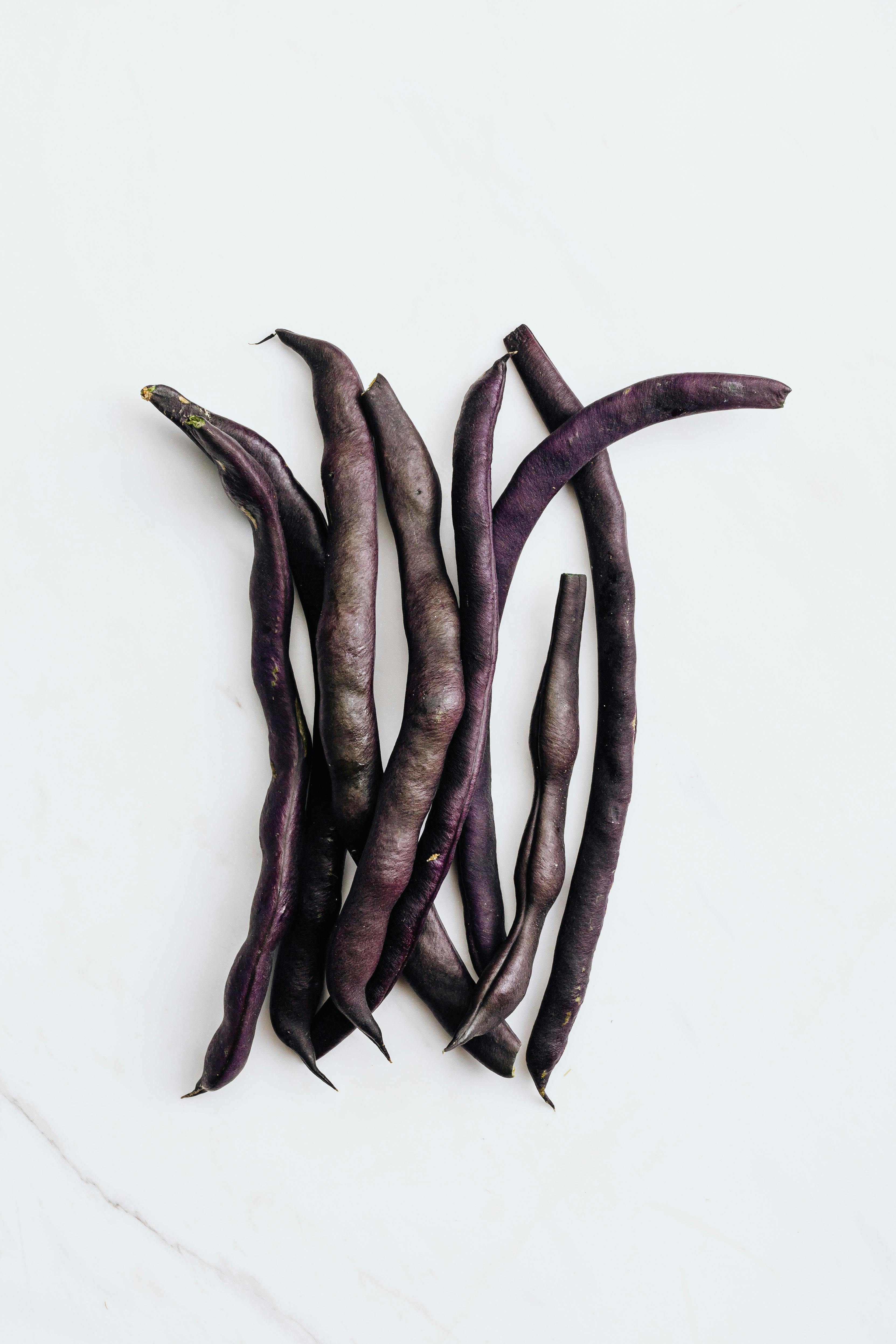 一束充满活力的紫豆优雅地排列在干净的白色表面上