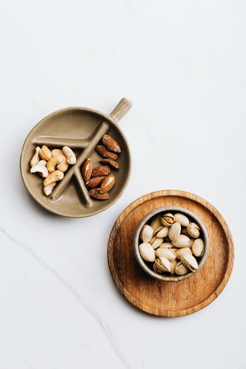 Pistachio, Almonds, Cashew Nuts on Wooden Plate on White Background