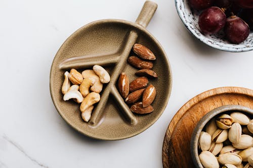 Gratis lagerfoto af cashewnødder, flatlay, keramiktallerken