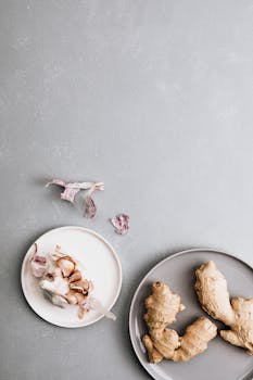 Elegant still life of garlic and ginger on simple plates, perfect for culinary arts.