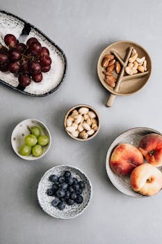 Top view of grapes, peaches, nuts, and berries on a textured gray surface.