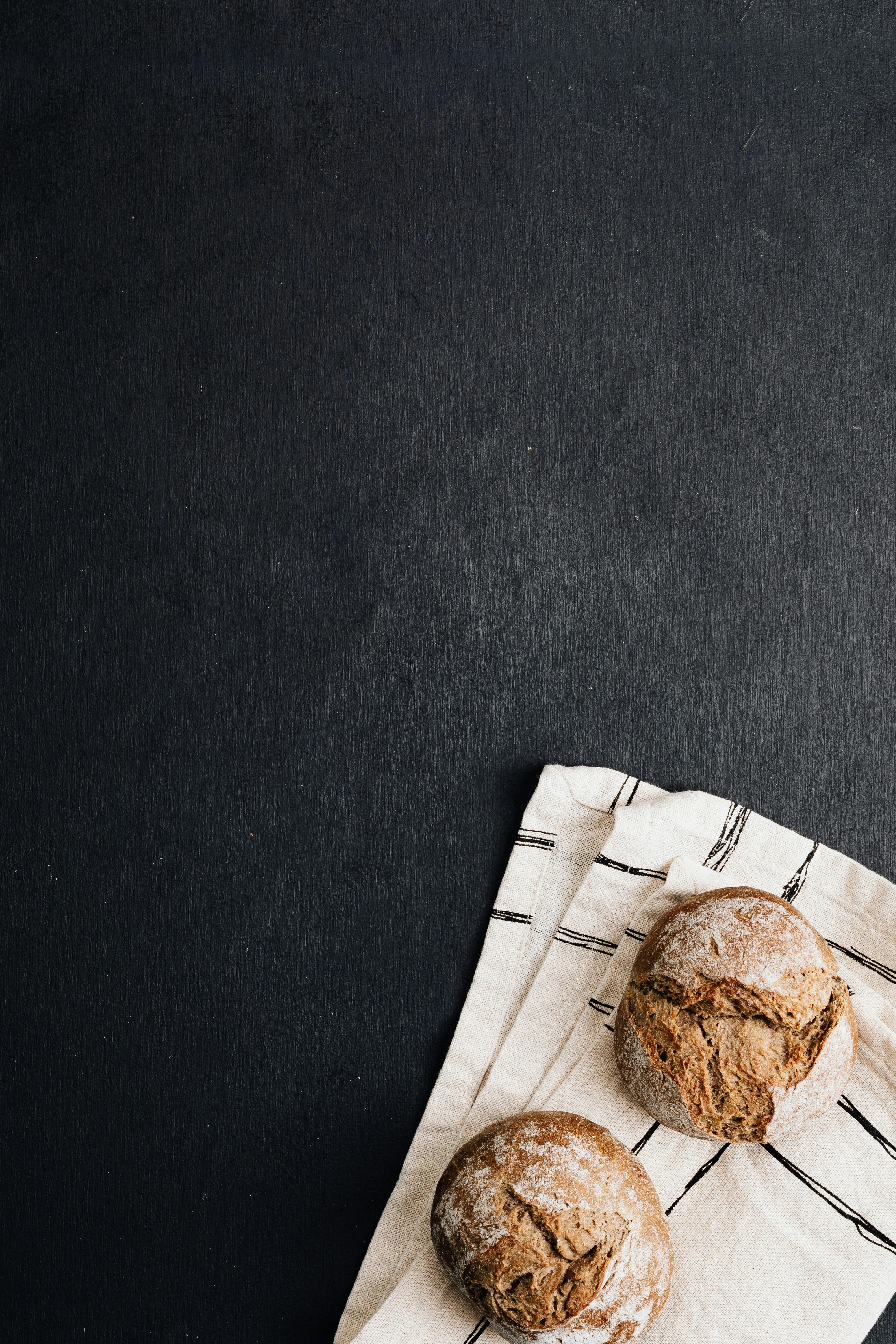 Two artisan bread buns on a striped cloth against a dark background, with copy space.