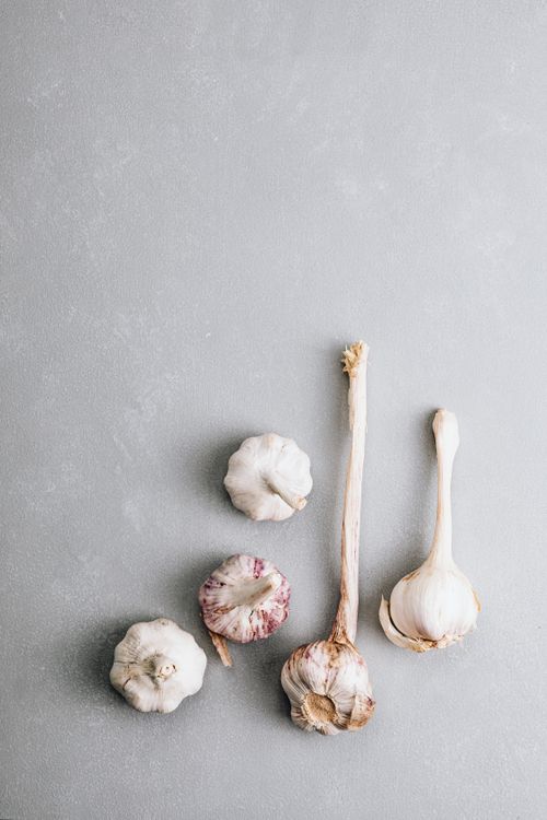 Free Aerial view of fresh garlic bulbs on a gray backdrop, suitable for food-themed designs. Stock Photo