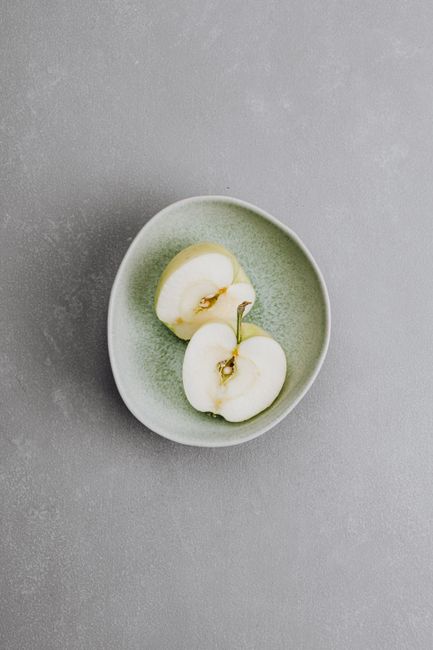 Aerial view of sliced green apple on a textured ceramic plate, ideal for healthy food content.