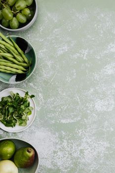 Top view of green vegetables and fruits in bowls, perfect for food blogs or healthy lifestyle marketing.
