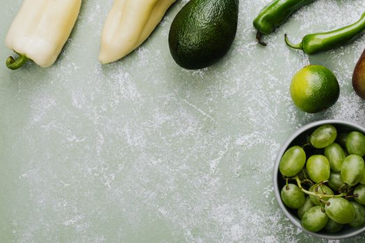 A vibrant selection of green fruits and vegetables arranged on a textured surface, perfect for healthy eating concepts.