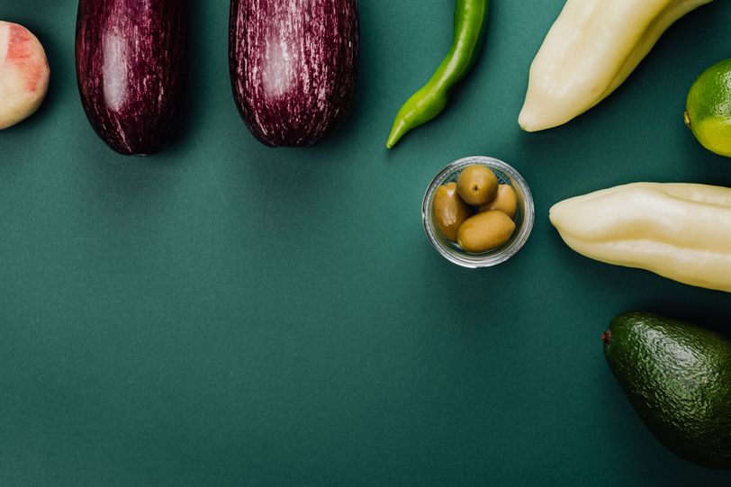 Fresh vegetables and olives arranged on a dark green surface — Kaboompics on Pexels