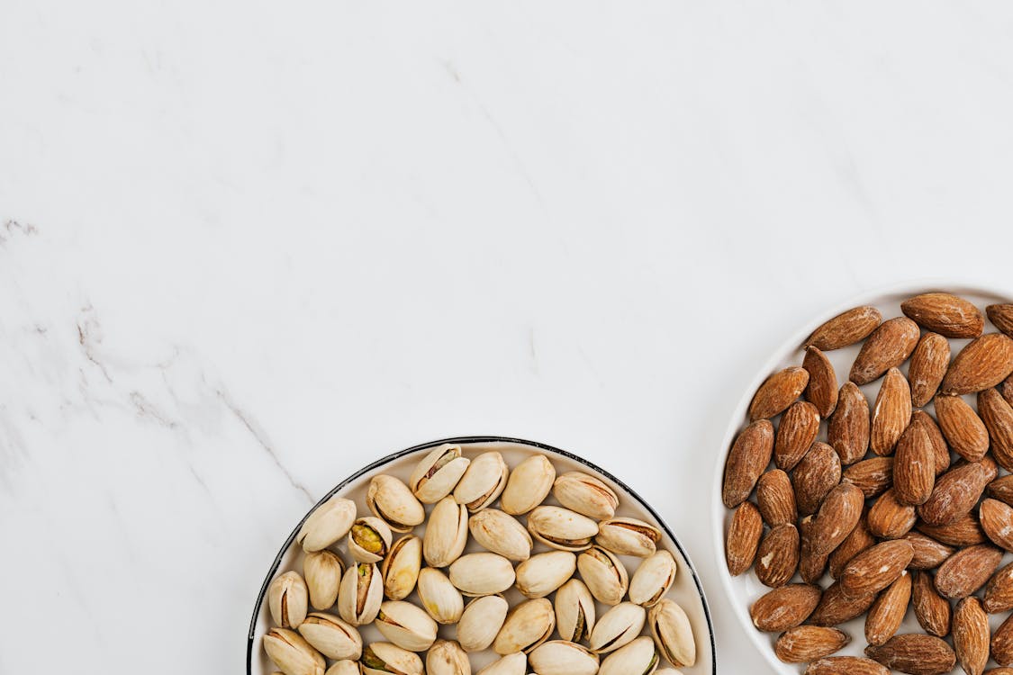 Free Almond and Pistachio on Plates On a White Surface Stock Photo