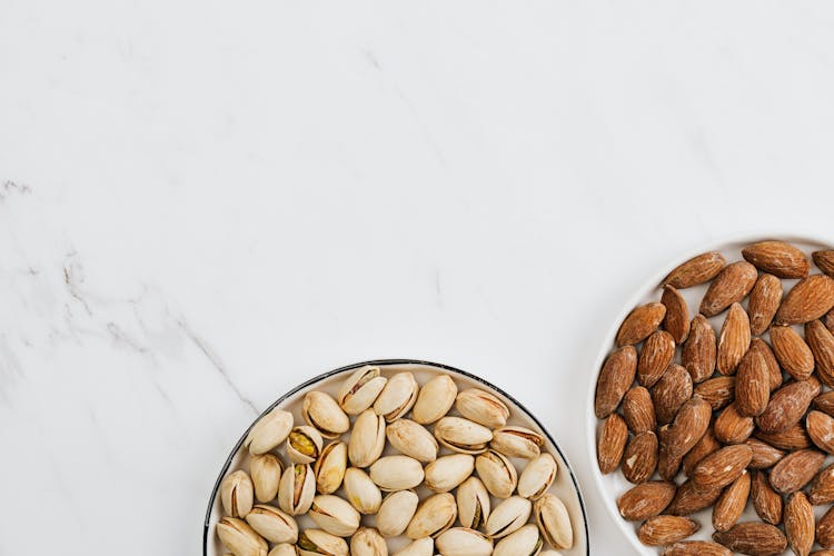 Almond And Pistachio On Plates On A White Surface