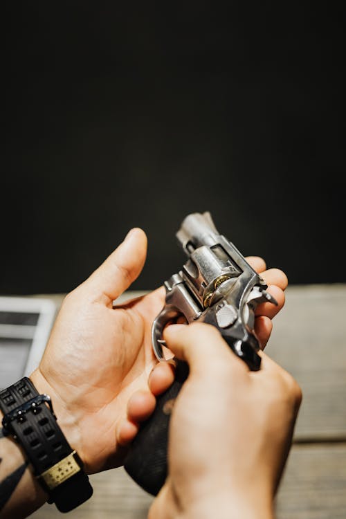 Hands of a Person Holding Silver and Black Handgun