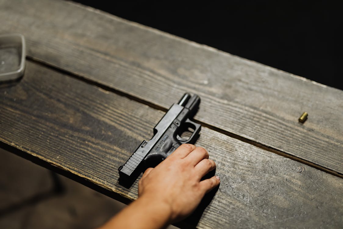 Free Hand of a Person Holding Black Semi Automatic Pistol Stock Photo