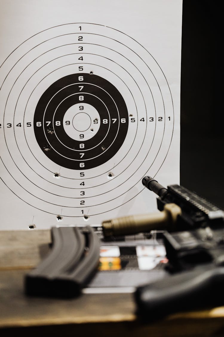 A Target Sheet Near A Rifle On Wooden Table