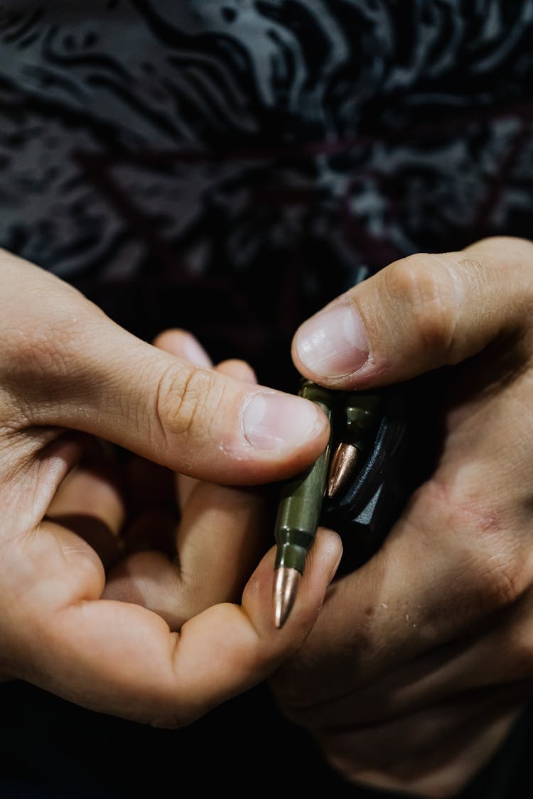 Close-Up Shot Of A Person Loading Bullet In A Gun