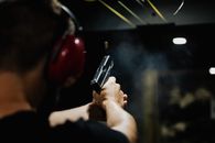 室内，一个人戴着耳罩射击手枪的后视图