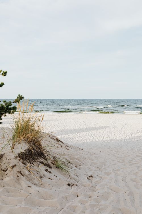 Free Tranquil sandy beach with gentle ocean waves under a cloudy sky, perfect for relaxation. Stock Photo