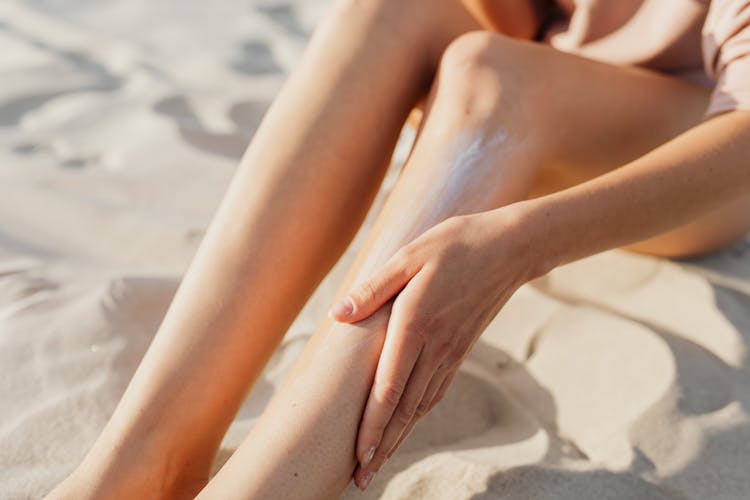 A Person Applying Cream On Her Leg