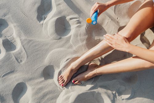 Free Woman Applying Sunscreen on Bare Legs Stock Photo