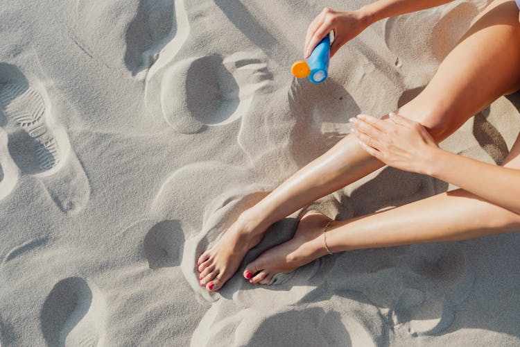 Woman Applying Sunscreen On Bare Legs