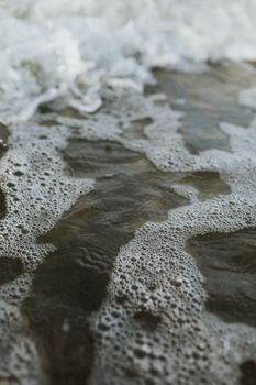 海浪拍打沙岸，泛起泡沫的特写镜头捕捉了自然的图案与纹理