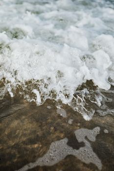 A dynamic close-up of ocean waves and sea foam, captured in natural light, showcasing intricate water textures.