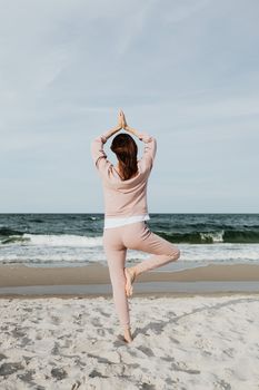 一名女子在宁静的海滩上练习瑜伽，拥抱自然与正念