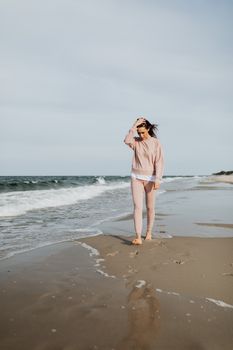 一名女子赤脚漫步在宁静的海滩上，身影映照出孤独与平静