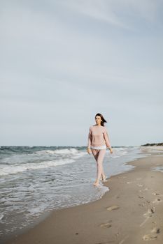 一名身穿粉红色服装的女子在宁静的海岸上平静地散步