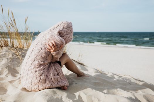 宁静的海滩上，一位穿着粉色针织衫的女子独自一人